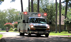 LifeNet Ground Ambulance travels down the road with lights flashing.