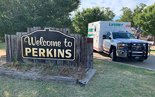 A LifeNet ambulance sits parked beside the Welcome to Perkins sign in Perkins, Oklahoma.